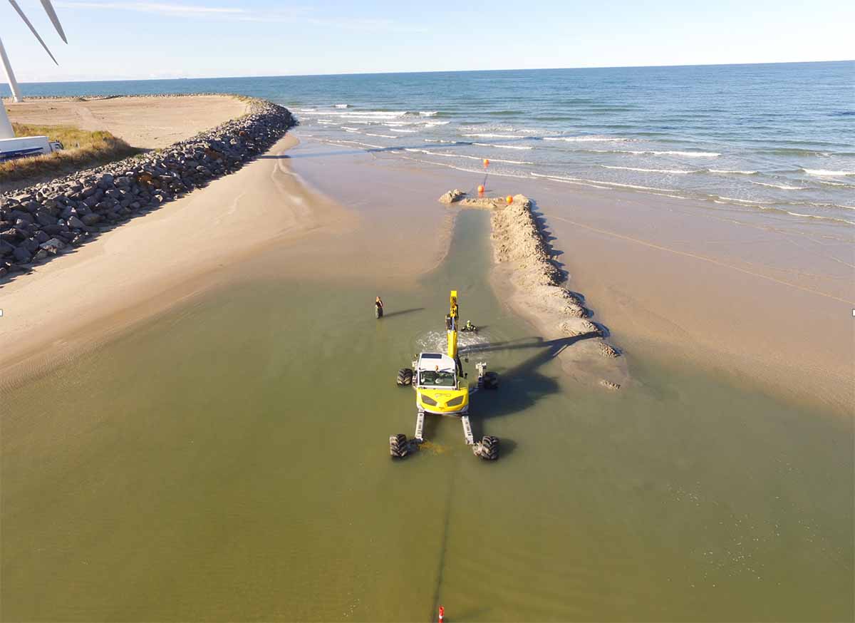 Graver grøft til ilandføring av kabel på strand - Dykkerteknikk AS